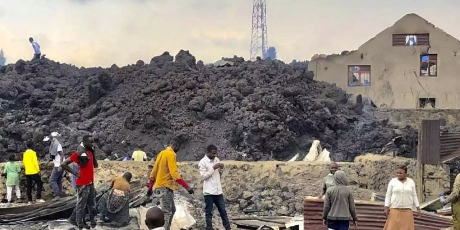 Menschen versammeln sich an einem Strom aus kaltem Lavagestein nach dem nächtlichen Ausbruch des Mount Nyiragongo in Goma. Foto: Clarice Butsapu/AP/dpa