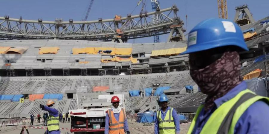 Bauarbeiter arbeiten am Lusail-Stadion, einem der Stadien der WM 2022. Foto: Hassan Ammar/AP/dpa