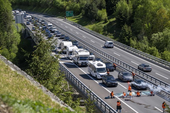Aktivisten von «Renovate Switzerland» protestieren vor dem Gotthardtunnel bei Göschenen im Kanton Uri, während dem sich der Auffahrt Reiseverkehr vor dem Gotthard Nordportal auf mehrere Kilometer staut. gotthard klima