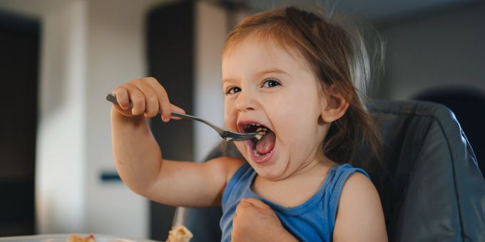 Kinder an den gemeinsamen Esstisch zu bekommen, kann herausfordernd sein. Kind beim Essen
