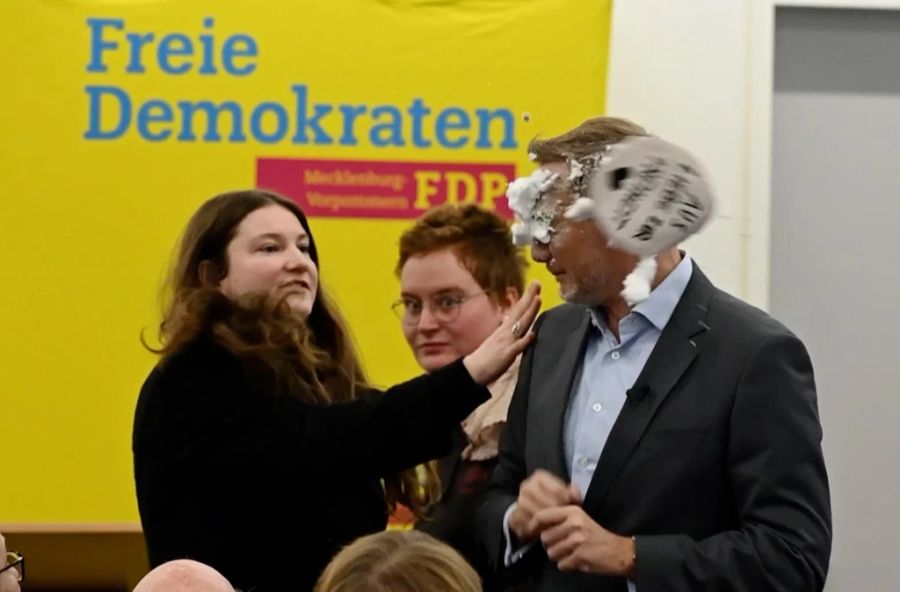 Der FDP-Vorsitzende Christian Lindner bekommt bei einem Wahlkampfauftritt in Greifswald von der Linke-Lokalpolitikerin Christiane Kiesow (l.) Schaum ins Gesicht geworfen.