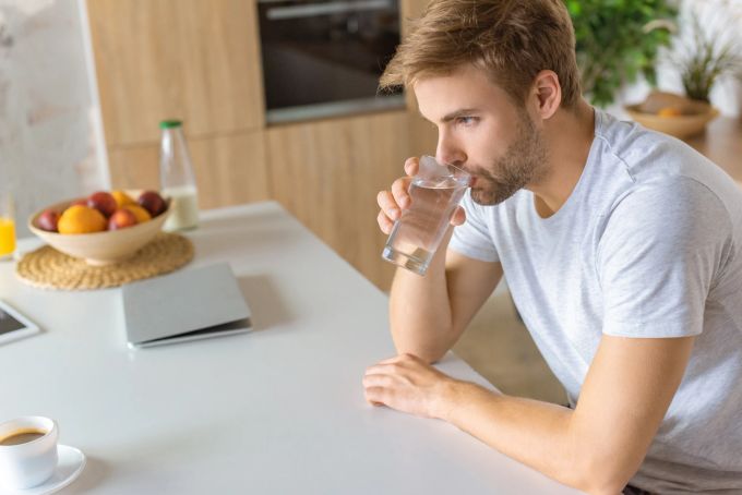 Trinke zwischen sechs und acht Gläsern Wasser täglich. mann trinkt wasser