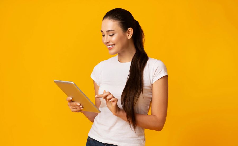 frau mit tablet vor gelbem hintergrund