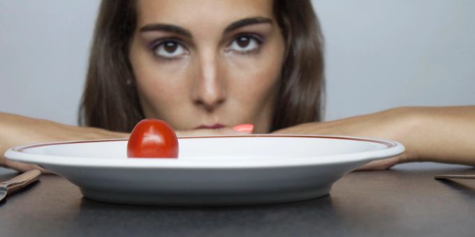 Wer sich nur von ein bisschen Gemüse und Obst ernährt, wird langfristig krank. Frau starrt Tomate auf dem Teller an