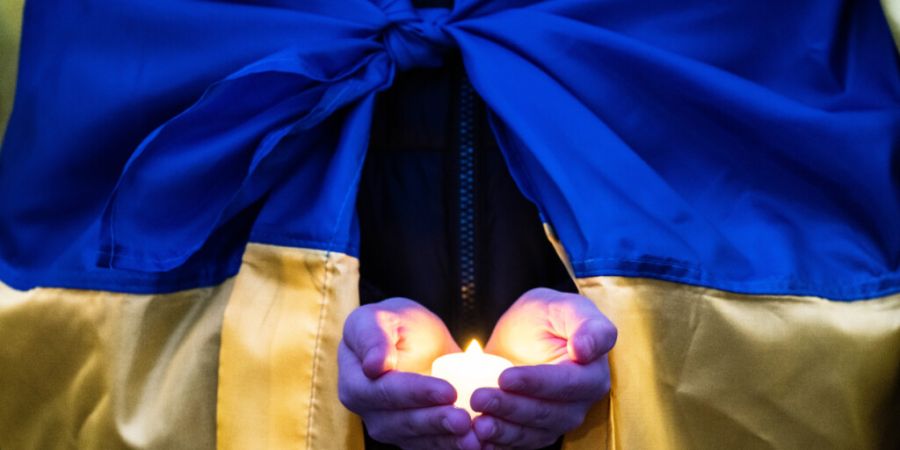 Eine Person hält eine Kerze in ihren Händen bei einer Kundgebung anlässlich des vierten Jahrestages der russischen Invasion in der Ukraine. Foto: Boris Roessler/dpa