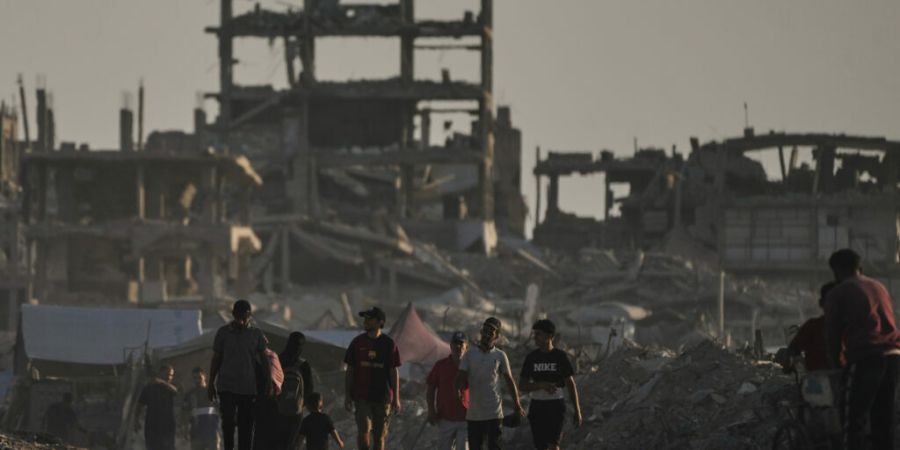 Palästinenser gehen in der Stadt Gaza zwischen den Trümmern von Gebäuden umher, die durch israelische Luftangriffe zerstört wurden. Foto: Jehad Alshrafi/AP/dpa