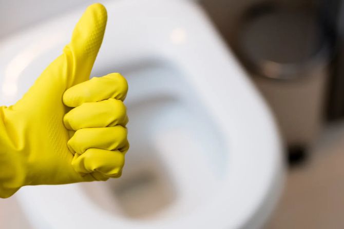 Handschuh mit Daumen hoch vor Toilette
