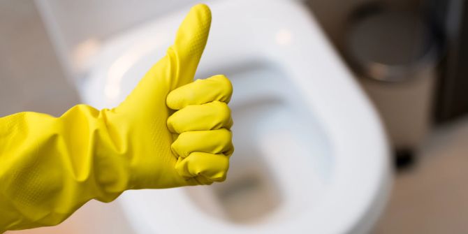 Handschuh mit Daumen hoch vor Toilette