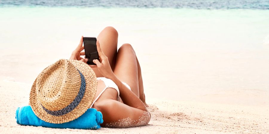Frau am Strand mit Handy.