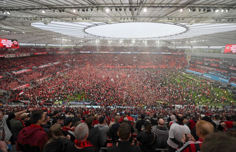 Die Fans von Bayer Leverkusen stürmen den Rasen.