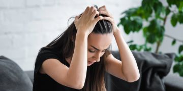 Verzweifelte Frau greift sich an den Kopf