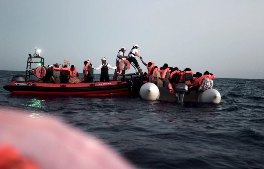 Seenotretter holen Flüchtlinge von einem kleinen Boot im Mittelmeer.