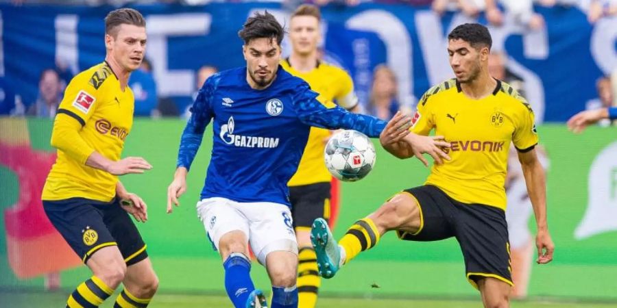 Dortmunds Achraf Hakimi (r) und Lukasz Piszczek (l) nehmen Schalkes Suat Serdar in die Zange. Foto: Guido Kirchner/dpa