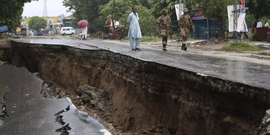 Soldaten gehen an einer stark beschädigten Strasse in Jatla vorbei. Foto: Anjum Naveed/AP