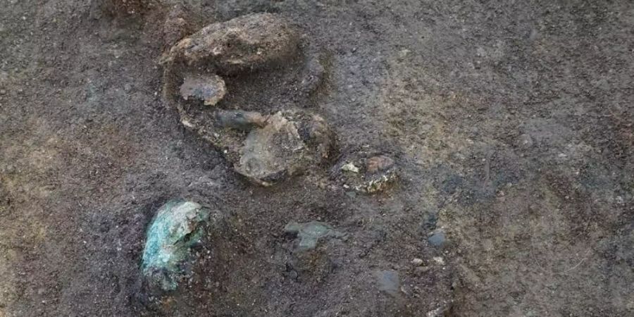 Teile eines Frauenschädels liegen neben Resten von Broschen. Bei Ausgrabungen rund 500 Kilometer nordwestlich von Oslo waren Wissenschaftler auf die Gräber eines Mannes aus dem 8. und einer Frau aus dem 9. Jahrhundert gestossen. Foto: Astrid Lorentzen/NTNU University Museum/dpa