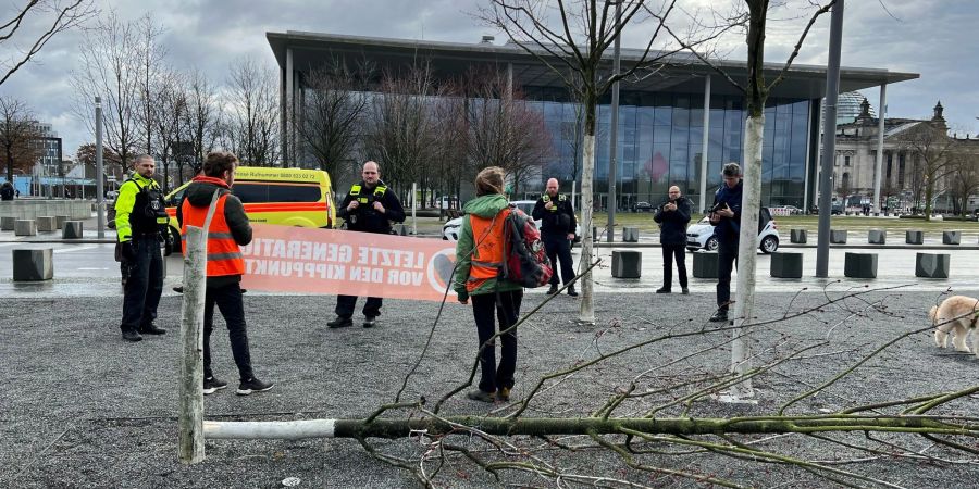 Klimaschutz-Demonstranten stehen an einem gefällten Baum am Bundeskanzleramt.