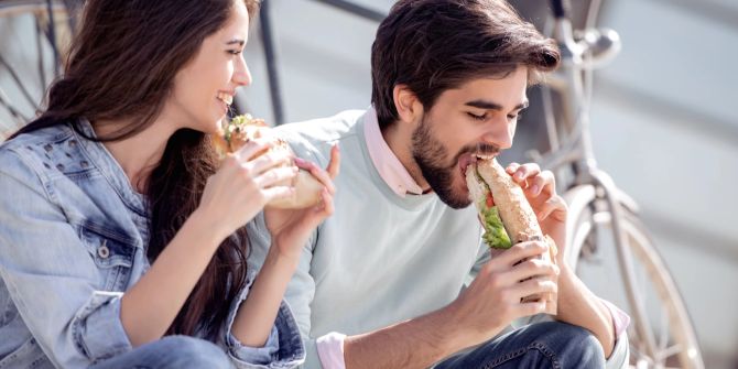 Mann und Frau geniessen ihr Essen im Freien