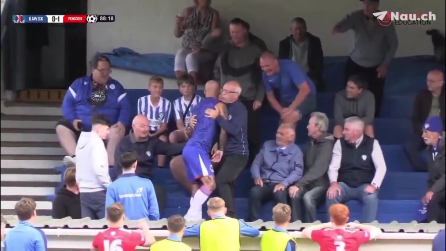 Ein Zuschauer versucht, Tansey festzuhalten und zu beruhigen, während der Spieler auf ihn zugeht.