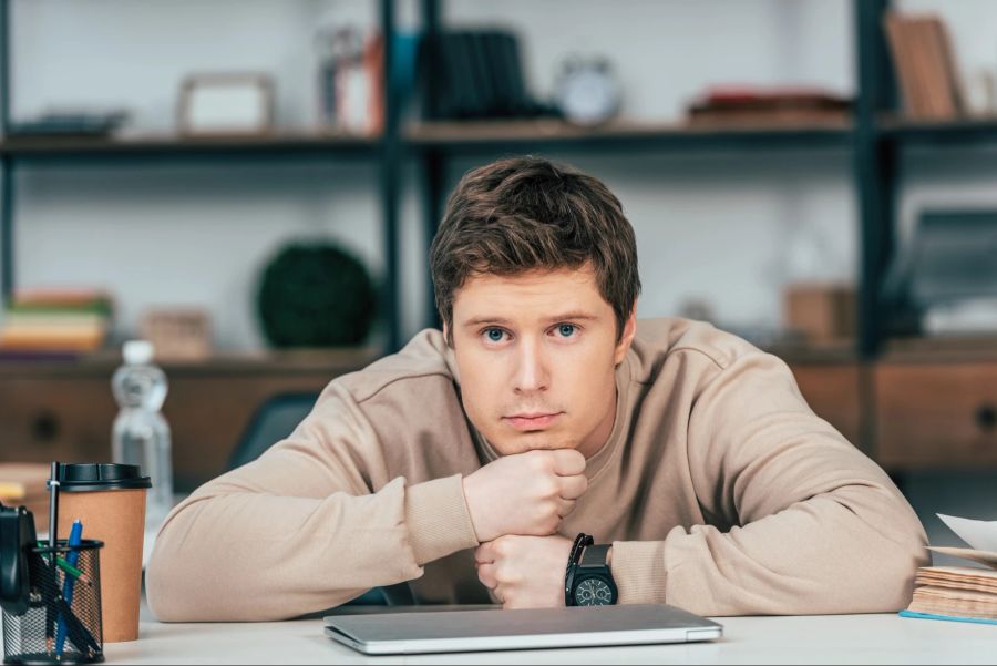 Mann vor zugeklapptem Laptop