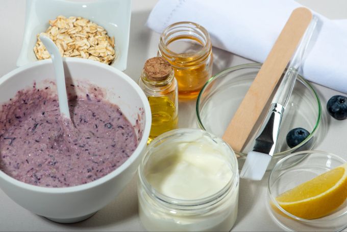 Blaubeeren sind voller Antioxidantien und können ganz leicht zu einer DIY-Gesichtsmaske verarbeitet werden. Blaubeermaske, Joghurt, Pinsel, Orange