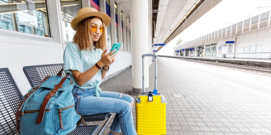 Frau Smartphone Bahnhof Koffer Rucksack Gleis Bank