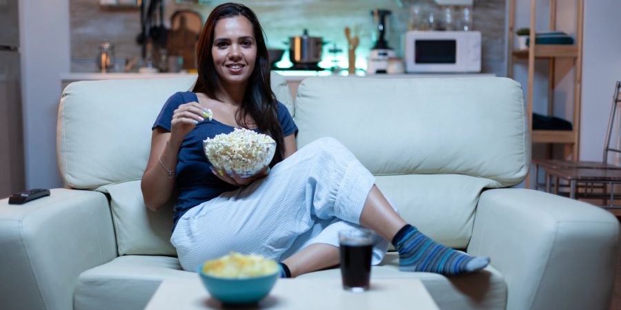 Frau mit Popcorn auf einem Sofa