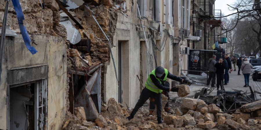 ARCHIV - Ein städtischer Arbeiter räumt die Trümmer eines Wohnhauses auf, das nach einem russischen Drohnenangriff beschädigt wurde. Foto: Oleg Grekov/AP/dpa