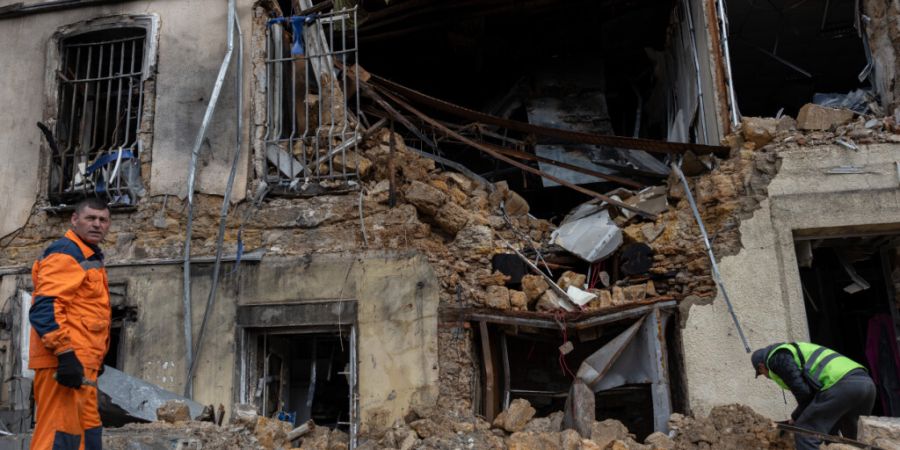 ARCHIV - Städtische Arbeiter räumen die Trümmer eines Wohnhauses weg, das durch einem russischen Drohnenangriff beschädigt wurde. Foto: Oleg Grekov/AP/dpa