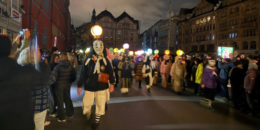 Tausende Maskierte marschieren gleichzeitig los – ein fliessender Zug aus Licht, Musik und Larven.