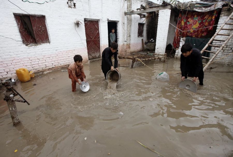 Pakistanische Kinder helfen, das Wasser aus den Häusern zu schöpfen.