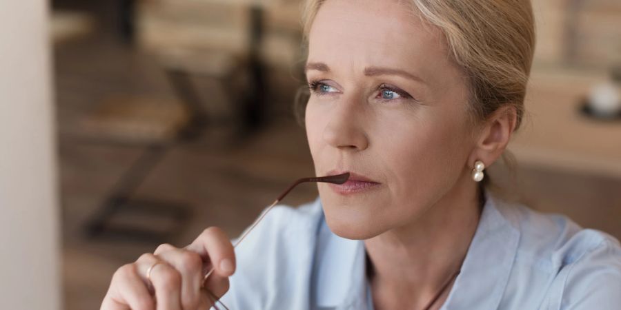 ältere, attraktive frau schaut aus dem fenster