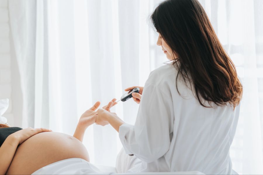 Schwangere bei Blutzuckermessung durch Gynäkologin