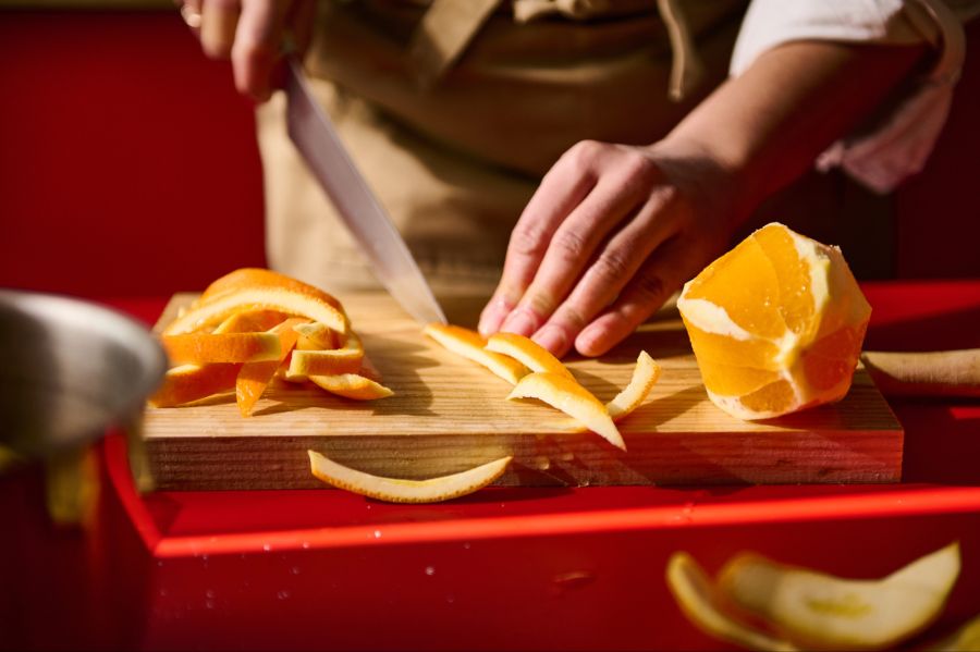 Person schneidet die Schale einer Orange