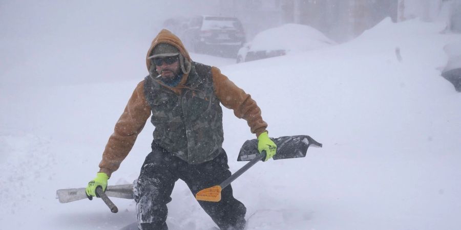 Travis Sanchez stapft mit zwei Schaufeln durch den Schnee in Buffalo, um einem gestrandeten Autofahrer zu helfen.