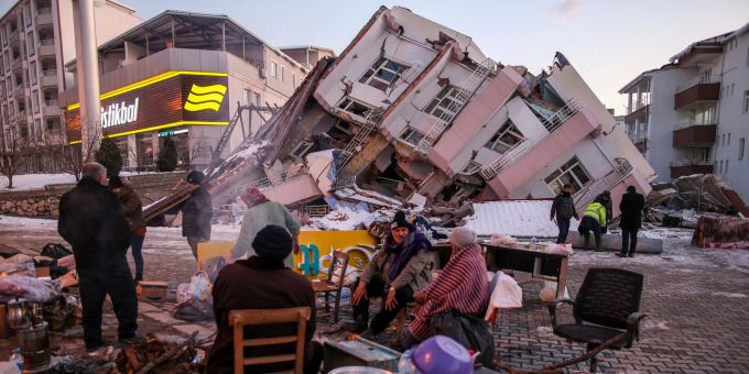 Leben in der Zerstörung: Menschen sitzen vor eingestürzten Gebäuden in Golbasi, Türkei. (Emrah Gurel/AP/dpa) erdbeben