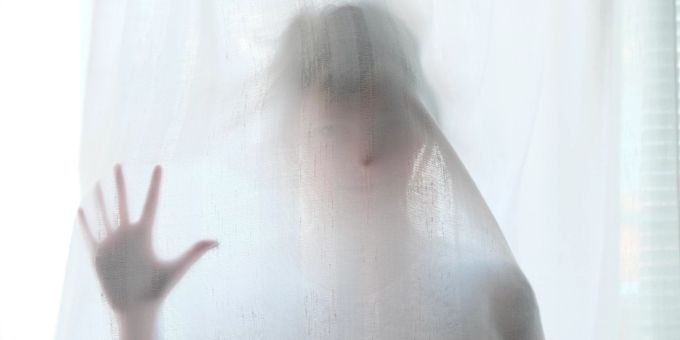 Angst ist nicht per se etwas Schlechtes. Frau hinter weissem Vorhang