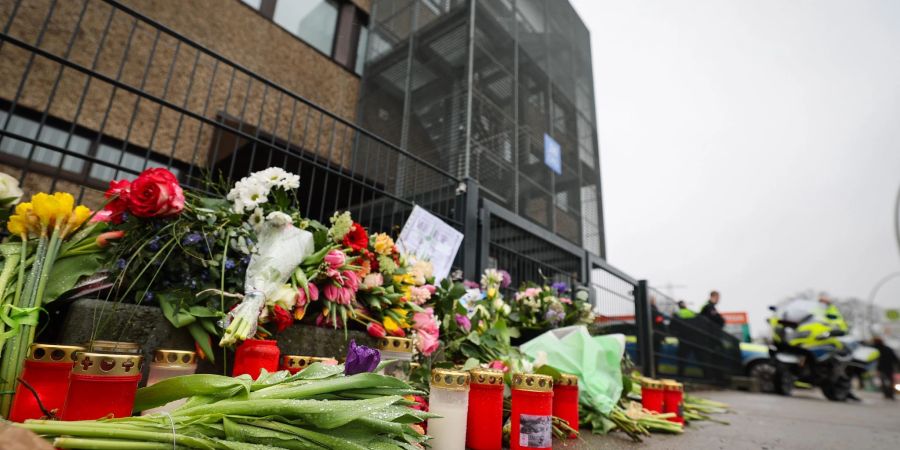 Blumen und Kerzen erinnern vor dem Eingangsbereich des Gemeindehauses in Hamburg an die Opfer der Amoktat.