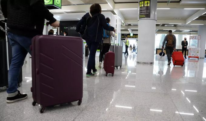 21.03.2021, Spanien, Palma: Fluggäste gehen mit ihren Koffern durch den Flughafen von Palma de Mallorca. Coronavirus auf Mallorca