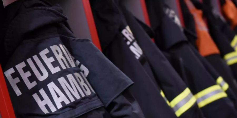 Feuerwehr-Einsatzjacken hängen in einer Feuerwache in Hamburg. Foto: picture alliance / Daniel Bockwoldt/dpa