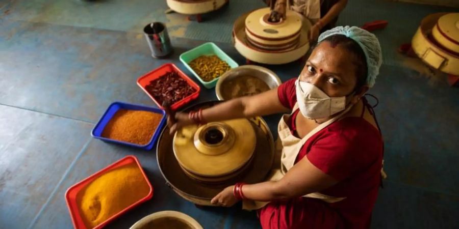 Eine Mitarbeiterin mahlt Gewürze in einer Handmühle in der in Neu Delhi ansässigen Anlage von ORCO, einer Marke, die Bio-Gewürze anbietet. Foto: Vijay Pandey/dpa