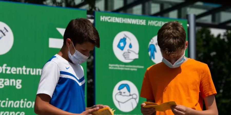 Die Geschwisterpaar blättert vor seiner Impfung am Impfzentrum auf dem Messegelände in Hannover in ihren Impfbüchern. Foto: Swen Pförtner/dpa