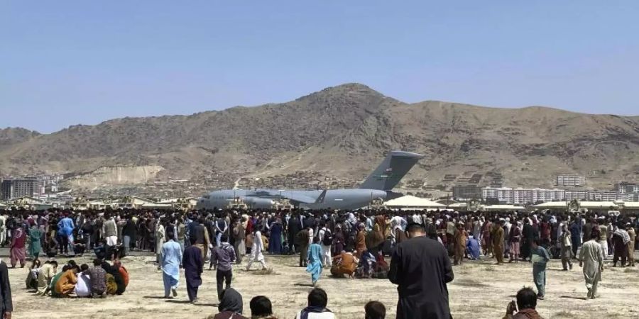 Hunderte Menschen haben sich auf dem Gelände des internationalen Flughafens in Kabul versammelt. Foto: -/AP/dpa