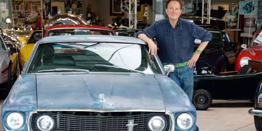 Der Oldtimerhändler Michael Fröhlich neben einem Ford Mustang, der einst dem US-Schauspieler Steve McQueen gehört hat. Foto: Henning Kaiser/dpa