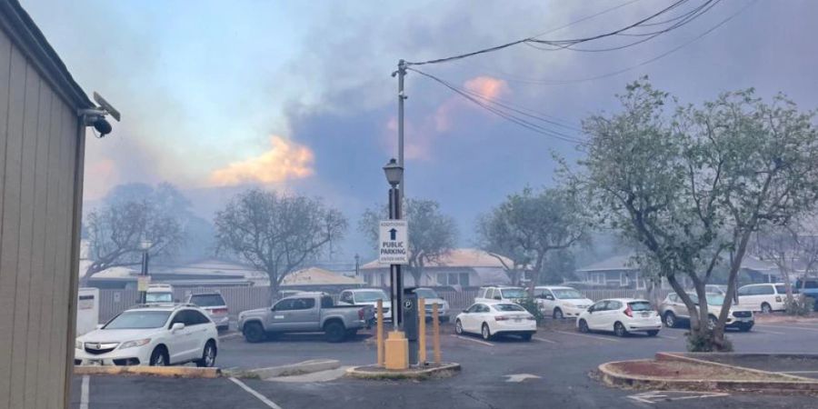 HANDOUT - Autos stehen auf einem Parkplatz in Lahaina, Hawaii während dahinter schon die Flammen hoch schlagen. Foto: Anatol Eisele/dpa - ACHTUNG: Nur zur redaktionellen Verwendung im Zusammenhang mit der aktuellen Berichterstattung und nur mit vollständiger Nennung des vorstehenden Credits