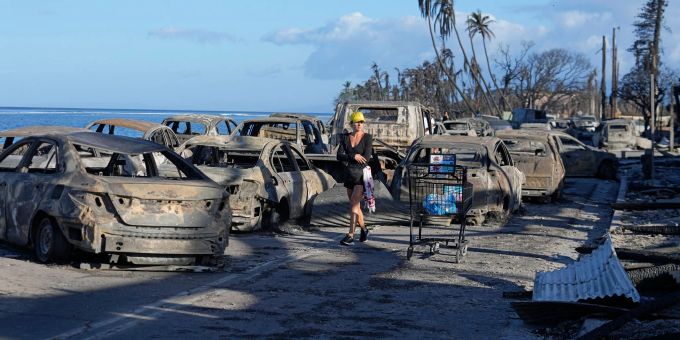 Eine Frau geht an zurückgebliebenen Trümmern nach dem Waldbrand in Lahaina vorbei. Eine Frau geht an zurückgebliebenen Trümmern nach dem Waldbrand in Lahaina vorbei.