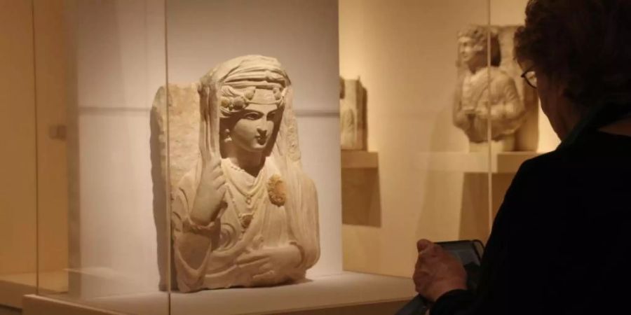 Besucher stehen vor einer antiken Stein-Büste der Bat'a, Tochter von Moqim, (Enkelin von) Malku aus Palmyra, die nach Expertenschätzungen im späten 2. oder frühen 3. Jahrhundert nach Christus entstanden sein soll. Foto: Christina Horsten