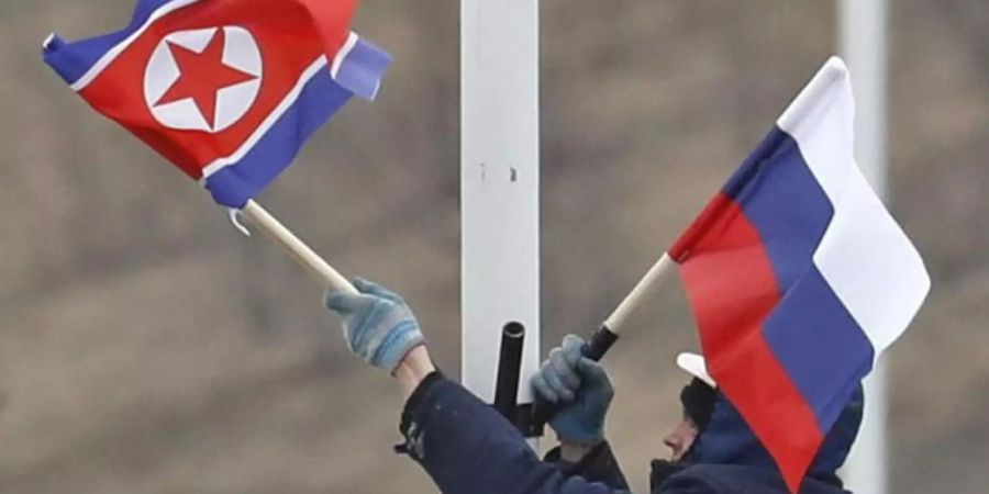 Vorbereitung auf das Treffen: Ein Arbeiter bringt an einer Strasse auf der Insel Russki vor Wladiwostok die Flaggen von Russland und Nordkorea an. Foto: Naoya Osato/Kyodo News/AP
