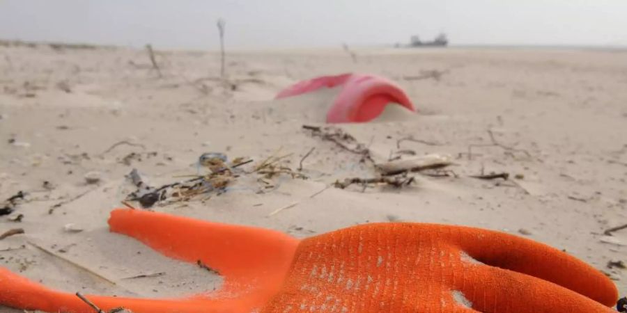 Angespülter Unrat in Form eines Arbeitshandschuhs und eines Kunststoffkanisters am Strand der Vogelschutzinsel Memmert, Niedersachsen. Foto: picture alliance / dpa