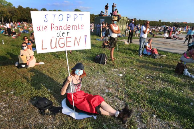 Eine Frau hält ein Transparent mit der Aufschrift «Die Pandemie der Lügen» in die Luft. Coronavirus