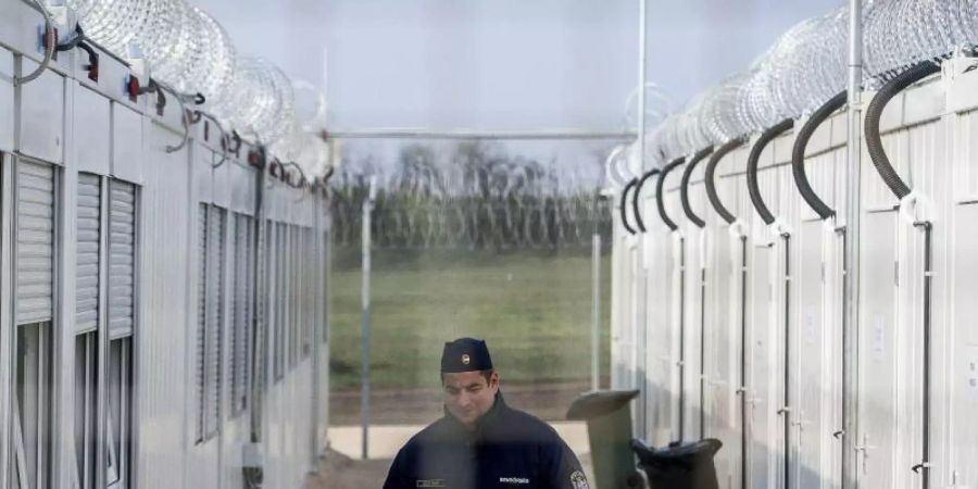 Ein ungarischer Polizist patrouilliert durch ein Lager für Asylsuchende an der Grenze zu Serbien. Foto: Sandor Ujvari/MTI/AP/dpa